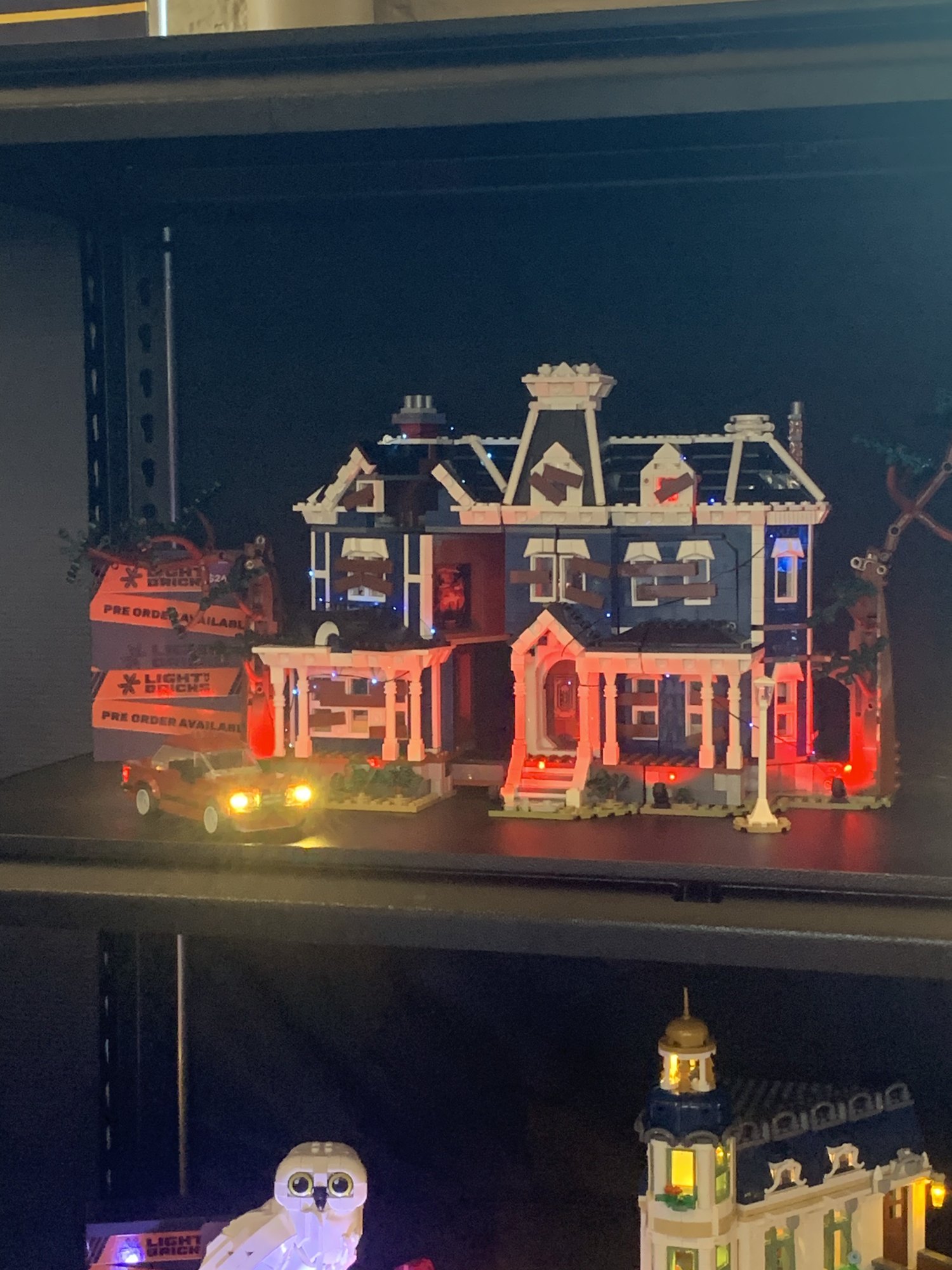 An illuminated LEGO haunted mansion on display at Brickvention, lit in red and blue.
