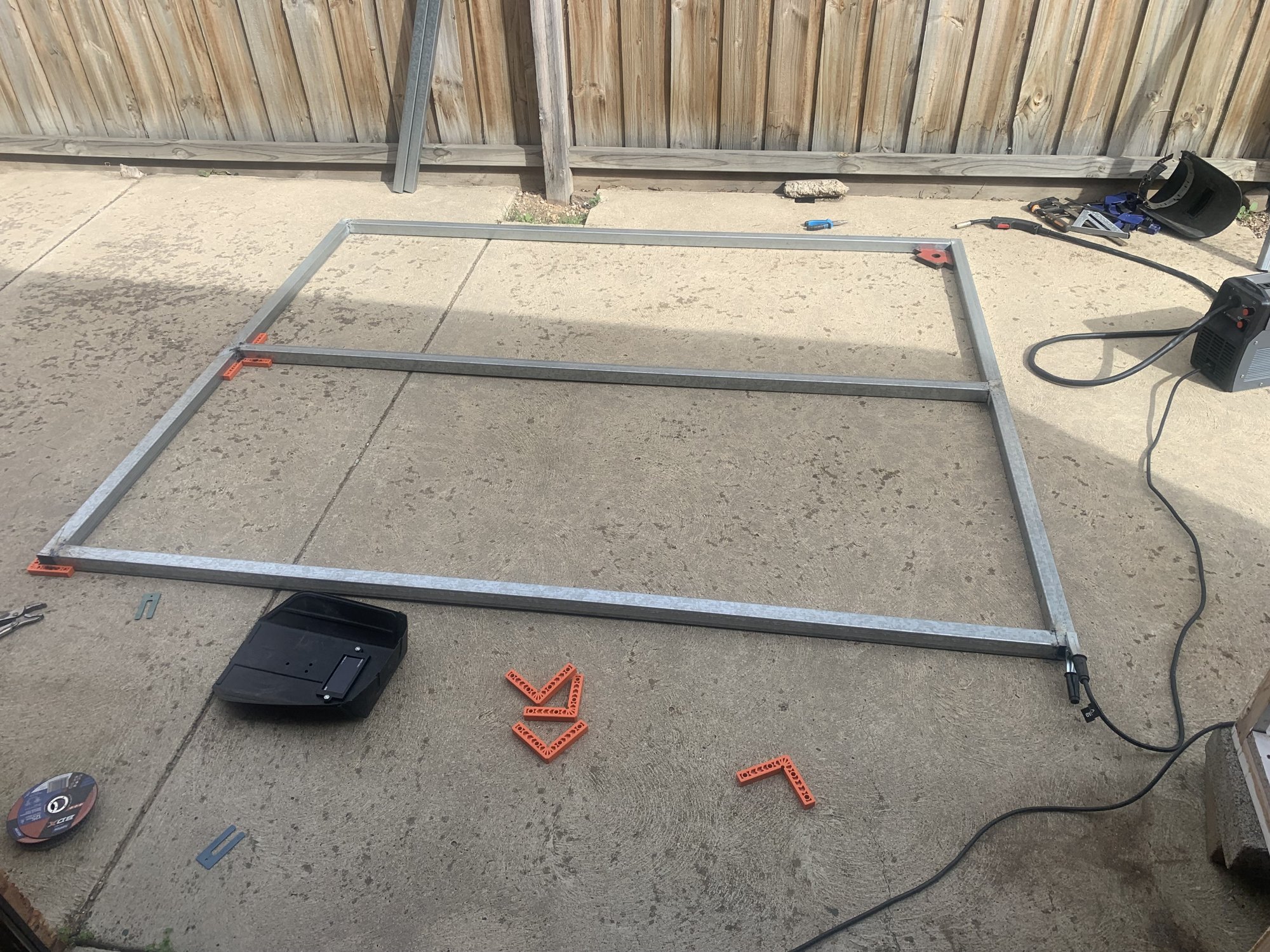 Before: a steel gate frame being measured and welded on the driveway.