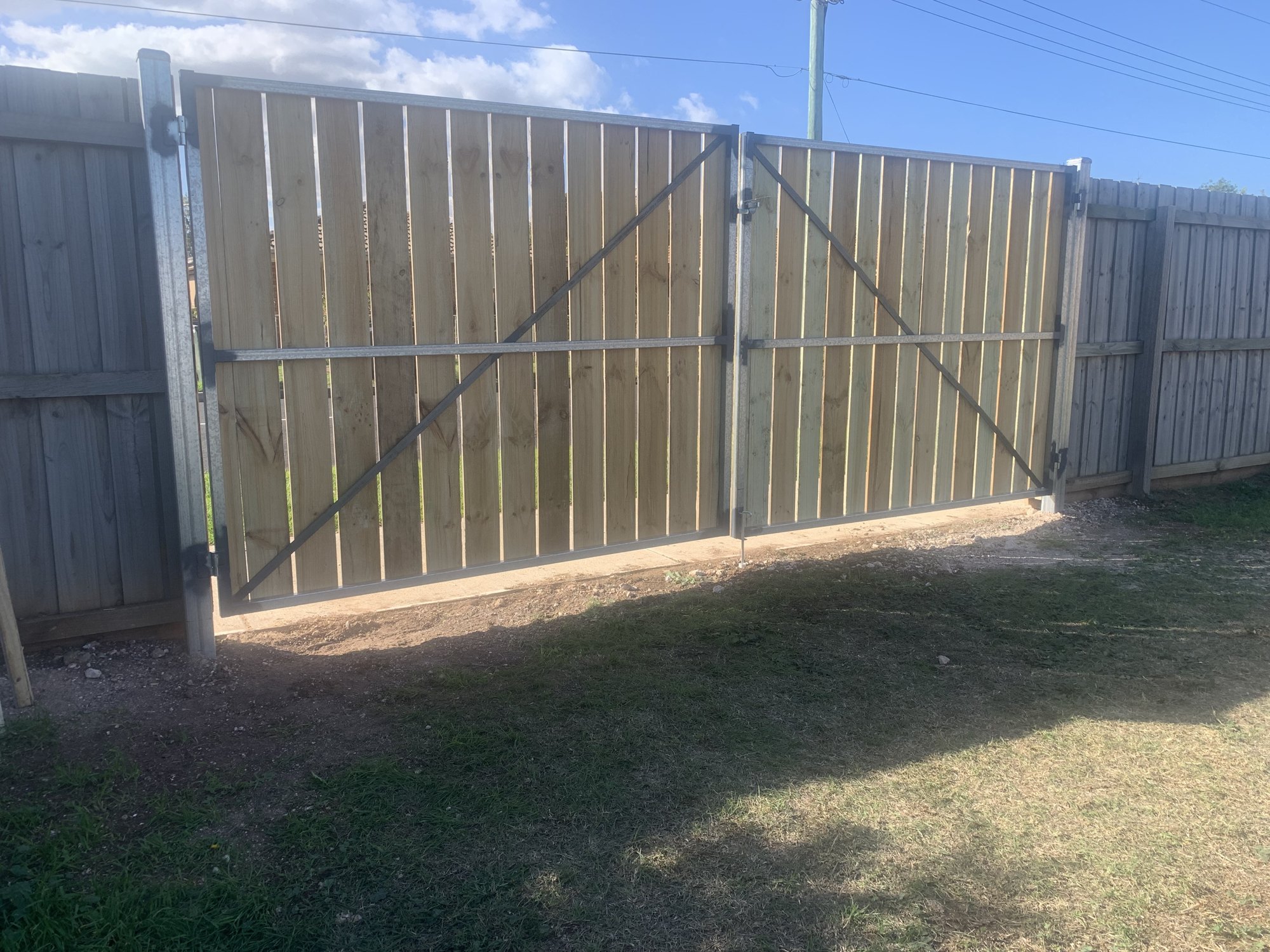 After: the finished double timber-and-steel gate, fitted and hung between fence posts.